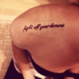 “fight off your demons” quote tattoo on girls shoulder