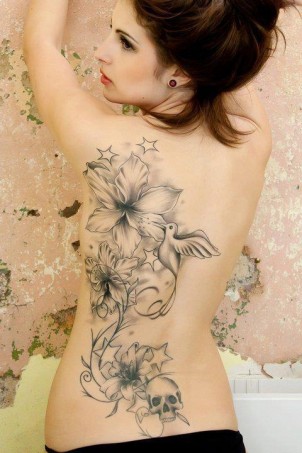 Black and white tattoo with flowers, stars, a bird and skull on girls back