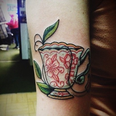 Cup of tea with flowers and leaves on girls leg
