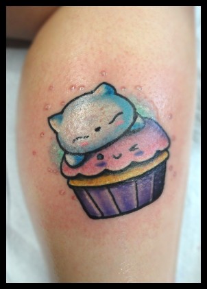 Cute cartoonish kitten on a cupcake tattoo