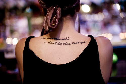 “You were once wild …don’t let them tame you” quote tattoo on girls back