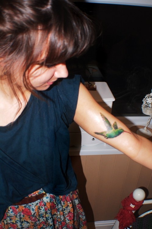 green hummingbird on girls arm