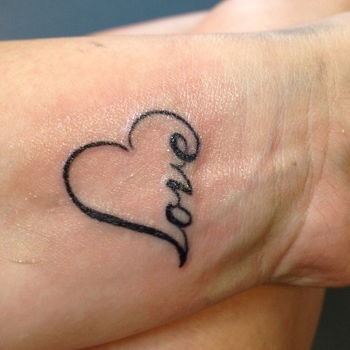 Girls heart wrist tattoo with love written in outline
