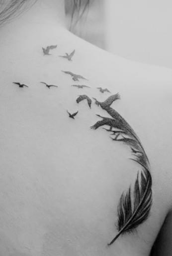 Brids flying from a single feather tattoo on girls back