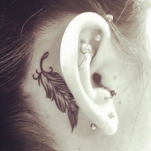small feather tattoo behind girls ear