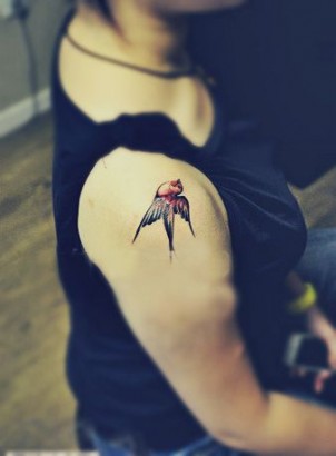 Red and black swallow tattoo on girls shoulder